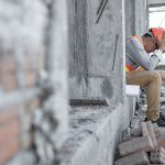 Construction worker sitting holding his head in his hands